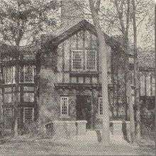  A two-story Tudor style building in a forest of tall trees