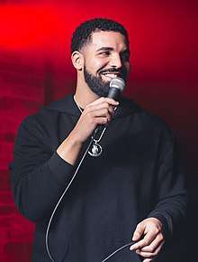 An image of Drake holding a microphone while looking away from the camera.