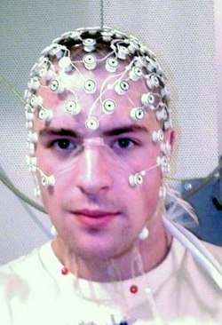 Photograph of a subject's head with numerous small sensors covering the forehead, neck and scalp