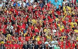 About a hundred Belgian football wearing mainly red shirts sitting in the stadium