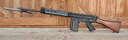A black FN FAL battle rifle with a wooden stock