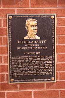 A bronze-and-black metal plaque hung on a brick wall displays an engraving of a man's face; the main caption of the engraving reads "Ed Delahanty; outfielder; Phillies 1888&ndash;1889, 1891&ndash;1901