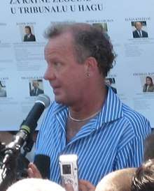Ed wearing a blue and white striped shirt, speaking into a microphone