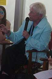 photo of Schüssler-Fiorenza, seated and speaking into a microphone