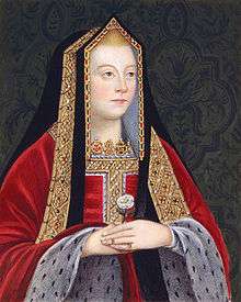 A blond woman with rosy cheeks holds a white rose. She wears a gilded black shawl over her head and a red robe trimmed in white spotted fur.