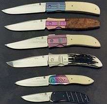 An assortment of knives with anodized titanium bolsters in bright colors