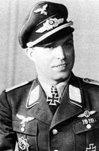The black and white photo of a man, shown from the front. He wears a military uniform with an Iron Cross displayed at the front of his shirt collar.