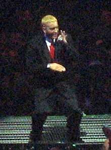 Eminem onstage, with blond hair and wearing a suit