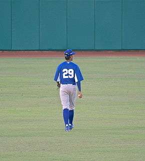 A man in a blue uniform walking toward the outfield in a baseball field.