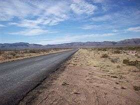 FM 1523, a two-lane road, traverses westward through a Chihuahuan Desert valley toward the Sierra Vieja.