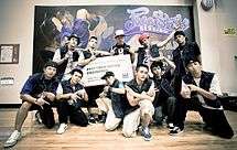 A group of eleven young men holding a large sign that says "BBoy Crew Battle Champion" while posing for a picture in front of a banner that says "Freestyle Session Taiwan".