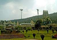 A far view of a temple complex with its gate, the sanctum, the gateway towers and a small garden being viewed.