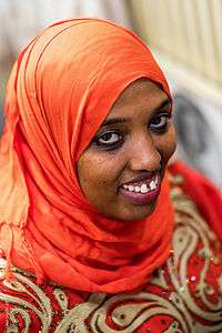 A smiling woman wearing an orange-colored hijab