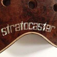 a tiny inlaid 'stratocaster' on a customised Fender guitar. the letters are mother of pearl and the wood is walnut burr