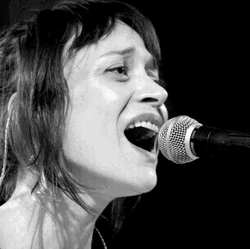 Black and white image of a woman singing into a microphone