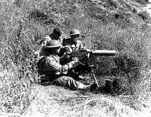 Three soldiers behind a M1917 Browning machine gun while training in a field in California