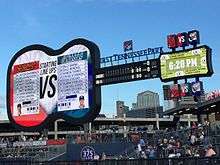 A giant guitar-shaped scoreboard behind the right field fence displays the starting lineup for players competing in the game, the game's line score, and the time.
