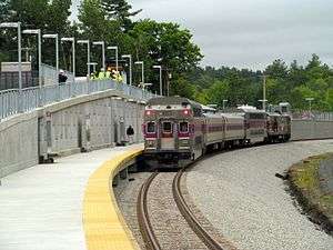 A silver and purple train at a station platform