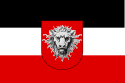 Tricolour flag of the German Empire with horizontal bands of black, white and red. Superimposed over it is an escutcheon of a silver lions head on a red background.