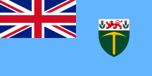 A sky blue flag with the Union Jack in the upper-left-hand corner, and a coat of arms on the right.