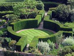 a circular enclosure of green hedging surrounding a lawn