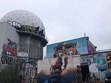An empty building and geodesic dome at the listening station are covered with various murals and graffiti.