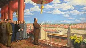 Mao stands on a balcony overlooking Tiananmen Square. He reads a speech with other leaders gathered behind him.