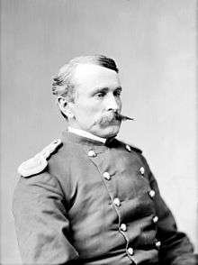 Head and torso portrait of a white man with a pointed mustache wearing a military jacket.