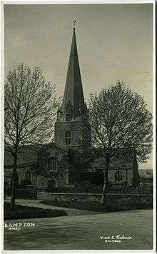 Sepia photograph of the church tower and spire, viewed between two trees