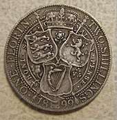 A silver coin, with three shields on it