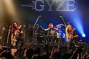 three Japanese male musicians perform on stage of a big concert hall