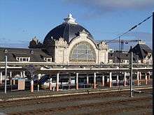 Train station with large, domed building and a high-speed train at the platform