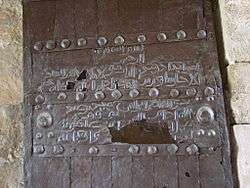 Photograph of an iron-covered door with Arabic inscriptions in two bands across it