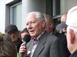 Gay Byrne speaking into a microphone in 2007 among people