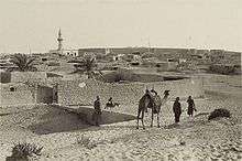 Walled town of El Arish, with camel and men in foreground