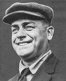 A smiling man wearing a newsie cap
