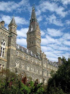 A large Gothic style stone building dominated by a tall clocktower.