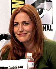 A redheaded woman, who is smiling at the camera.