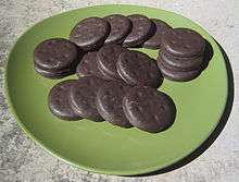 Sixteen Thin Mints spread out on a green plate.