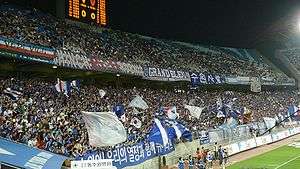 A stand full of Korean fans cheering after a goal.