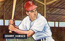 A baseball card image of a man holding a baseball bat over his right shoulder; he is wearing a white baseball jersey and red baseball cap with a white "P" on the front