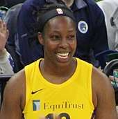 Young woman wearing yellow basketball uniform smiling broadly