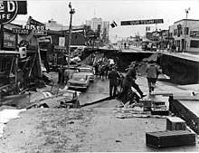 Photograph of Fourth Avenue, a street in Anchorage, showing the damage caused by the Great Alaska Earthquake, 1964. Photo by the U.S. Geological Survey.