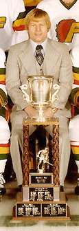 Gregg Pilling sitting behind the Lockhart Cup in a team photo of the 1976-77 Philadelphia Firebirds