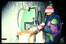 Scientist standing at a bench, sawing an ice core