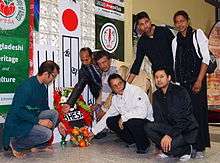 People laying flowers at a simple indoor shrine