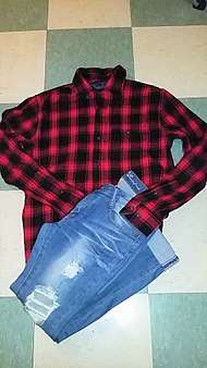a red-and-black flannel shirt and intentionally-distressed blue jeans