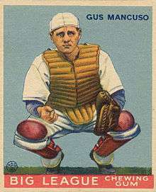 A baseball-card image of a man in a white baseball uniform wearing shin pads on his legs, a chest protector, and a catcher's mitt on his left hand