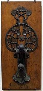 Art Nouveau-style metal door knocker on a wooden door