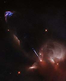 Images are in false colour. Bright yellow star in brown-appearing nebula shoots out a blue-white jet, which then causes blue and purple emissions from the surrounding medium upon impact